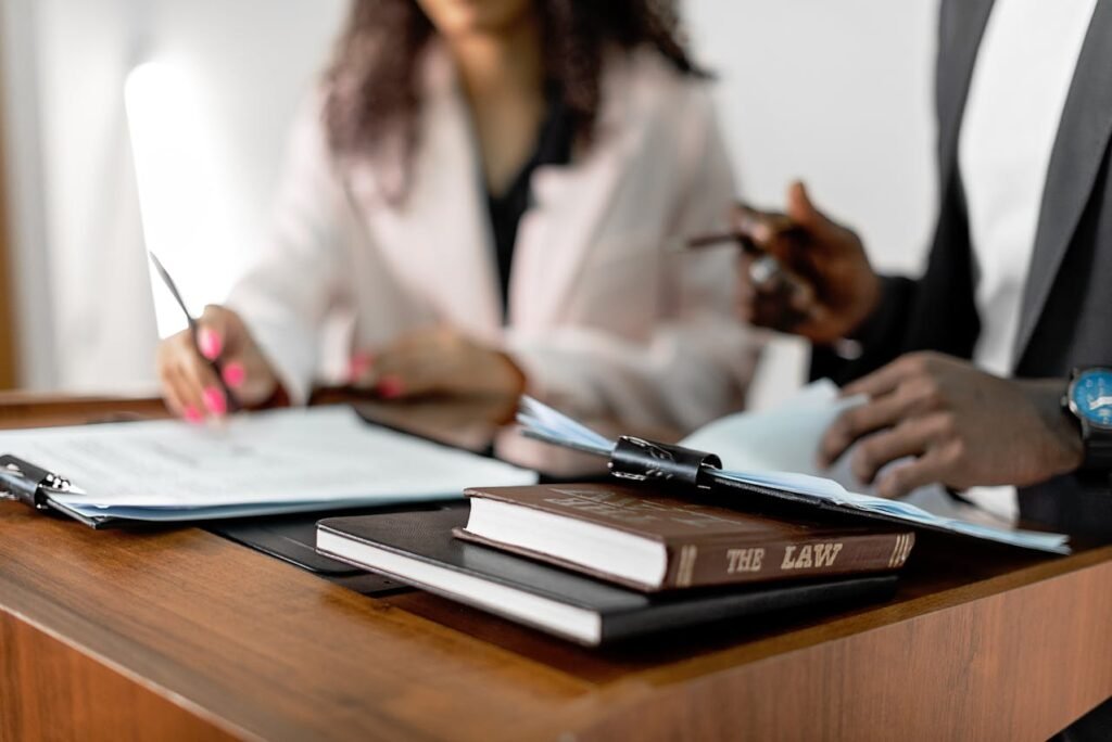 Two professionals review legal documents at a desk, with law books
