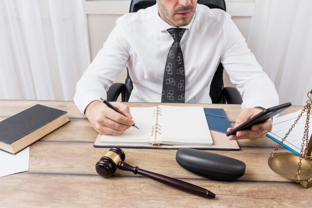 Man at desk with gavel, phone, and notebook.